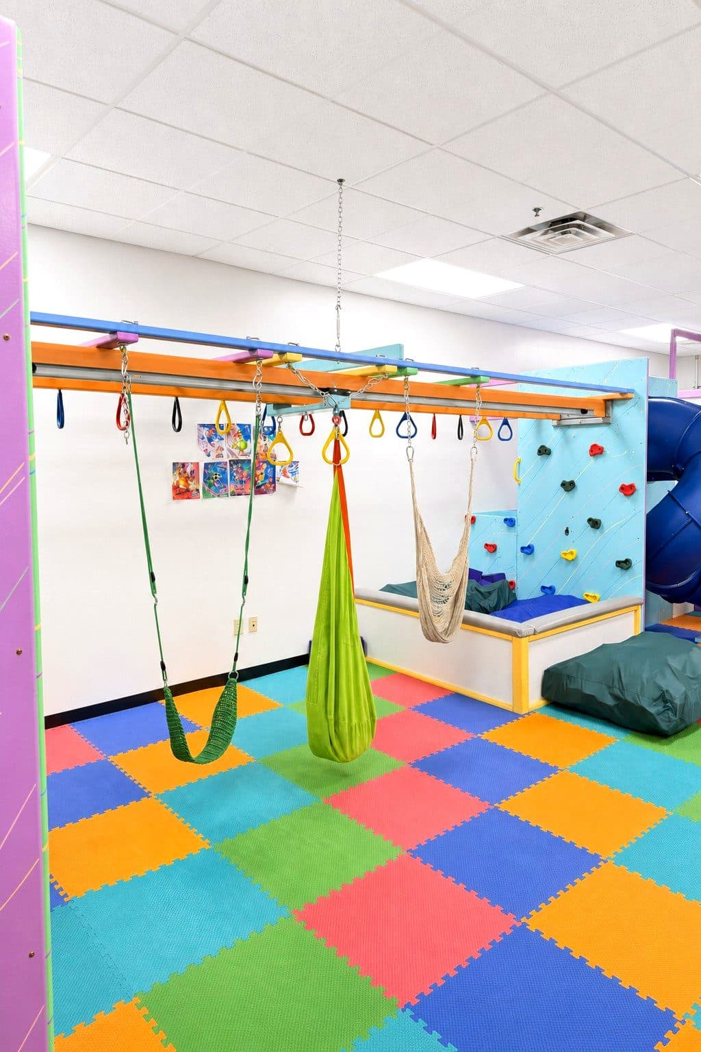 The sensory gym at our Eagan clinic, with therapy swings and bright foam-tile flooring